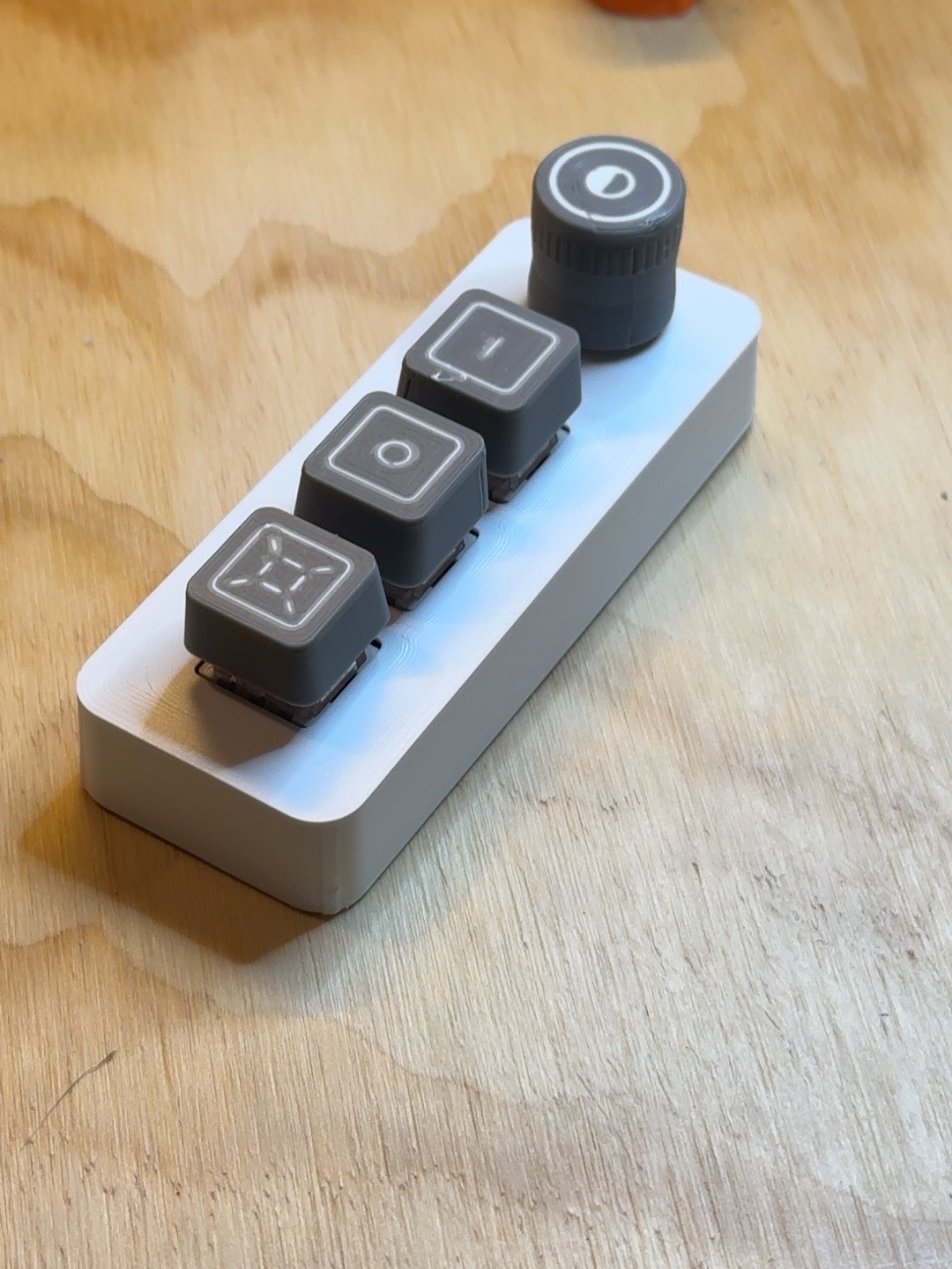 VisiDial physical prototype on a wooden desk, showing the rotary knob and three vertically stacked buttons.