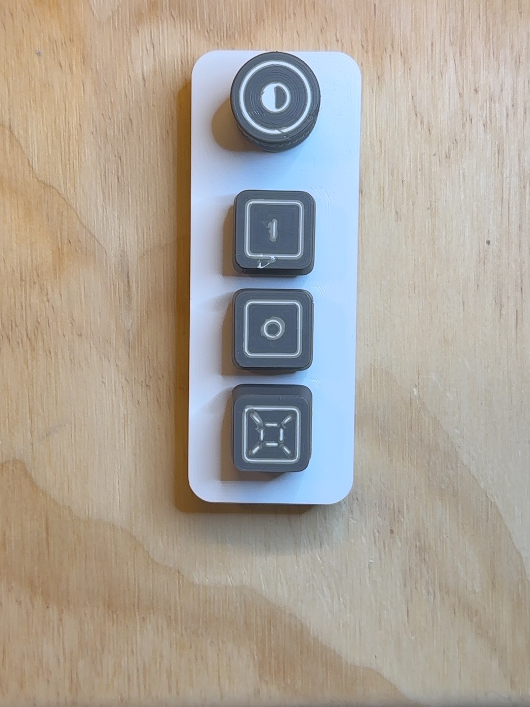 Top view of a VisiDial prototype with a rotary knob above three vertically stacked buttons marked 1, 0, and Overview.