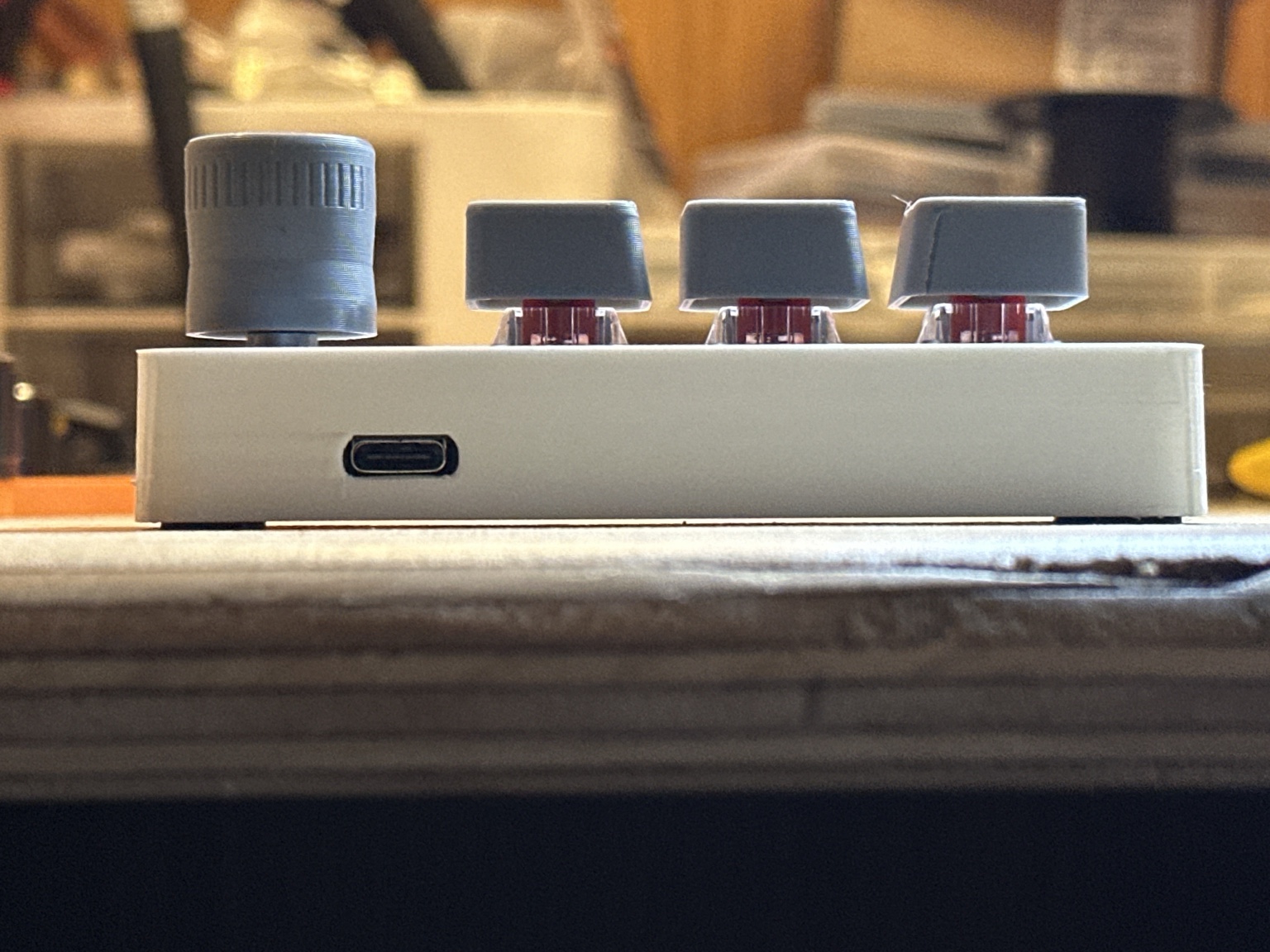 Side view of a VisiDial physical prototype showing its USB-C connection, rotary knob, and three buttons.